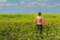 Woman hiker in the middle of a field of yellow flowers