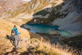 Woman hiker in the mountains and lake at background. Tourist woman descend from the mountain