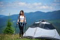 Woman hiker near camping in the mountains with backpack and trekking sticks in the morning Royalty Free Stock Photo
