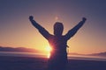 Woman hiker open arms under the sunrise at sea