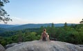 Woman hiker seated alone on rocky mountain cliff enjoying view of evening nature on wilderness trail. Active way of life Royalty Free Stock Photo