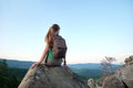 Woman hiker seated alone on rocky mountain cliff enjoying view of evening nature on wilderness trail. Active way of life Royalty Free Stock Photo