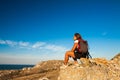 Woman hiker sits on seaside mountain rock Royalty Free Stock Photo