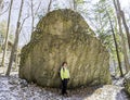 Woman hiker stops beside huge boulder to marvel at wilderness en