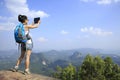 Woman hiker taking photo with digital camera at mountain peak
