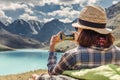 hiker taking photo of a mountain lake on her smartphone Royalty Free Stock Photo
