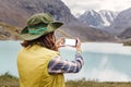 Hiker taking photo of a mountain lake on her smartphone Royalty Free Stock Photo
