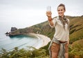 Woman hiker taking selfie with smartphone in front of ocean Royalty Free Stock Photo