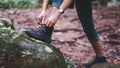 A woman hiker tying shoelaces and getting ready for trekking in the forest Royalty Free Stock Photo