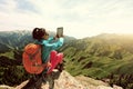 Woman hiker use digital tablet taking photo on mountain peak cliff Royalty Free Stock Photo