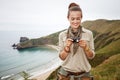 Woman hiker viewing photos in front of ocean view landscape