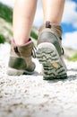 Woman hiker walk on a rocky ground. Sunny day.Trekking boots.Lens flare. Succesful backpacker. Stone. Step