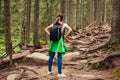 Woman hiker walking through mountain forest path surrounded with roots in Carpathians. Traveler with backpack resting Royalty Free Stock Photo