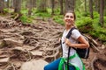 Woman hiker walking through mountain forest path surrounded with roots in Carpathians. Traveler with backpack resting Royalty Free Stock Photo