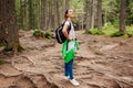 Woman hiker walking through mountain forest path surrounded with roots in Carpathians. Traveler with backpack resting Royalty Free Stock Photo