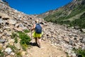 Woman hiker wearing a backpack and using trekking poles makes her way across scree along the Lake Solitude trail in Grand Teton