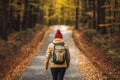 Woman with backpack and knit hat hiking in autumn forest Royalty Free Stock Photo