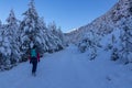 Woman with hiking backpack on a heavy snow covered trail with fir tree in winter wonderland forest in Bad Bleiberg, Carinthia