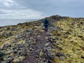 Woman hiking on coastal path from Djupalonssandur to black beach of Dritvik in Snaefellsnes Peninsula, Iceland.