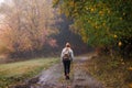 Woman hiking on footpath in autumn forest. Fog weather Royalty Free Stock Photo