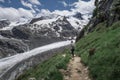 Woman hiking at Morteratsch Glacier in the Engadin in the Swiss Alps in summer with blue sky and sun