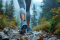 Woman hiking in rainy mountain wilderness with waterproof boots on rocky trail through lush forest. Royalty Free Stock Photo