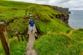 Woman hiking on a rainy day from Doolin to the Cliffs of Moher along the spectacular coastal route walk Royalty Free Stock Photo