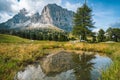 Woman hiking in Val Gardena. Pond and reflection of Sassolungo Langkofel mountain. Dolomites, Italy