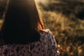 woman hipster hair at sunset in summer field. back view. atmospheric moment. boho girl relaxing in meadow in beautiful sunlight. Royalty Free Stock Photo