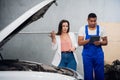 Woman hires a mechanic in overalls to repair a car