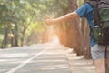 Woman hitchhiker with backpack sign thumb up on highway road.