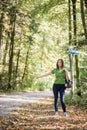 Woman hitchhiker standing on the side of the road in autumn fore