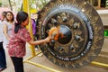 Woman hits gong with a hammer visiting Wat Pho Chai buddhist temple in Nong Khai, Thailand.