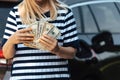 Woman hold cash dollar bills next to car with an open tank, concept of rising fuel prices Royalty Free Stock Photo