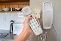 Woman hold landline telephone at the house wall