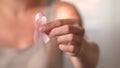 Woman hold pink ribbon. Close up view of hand with symbol of national breast canser awareness month in october