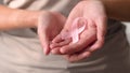 Woman hold pink ribbon. Close up view of hand with symbol of national breast canser awareness month in october