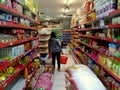 A woman hold a red shopping basket searching items on the racks in the aisle of supermarket, Royalty Free Stock Photo