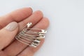 Woman hold set of metall safety pins for crafts, fashion, jewelry, hobby or household on white background. Isolated Royalty Free Stock Photo