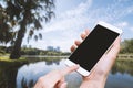 Woman hold smart phone and touch button by hand with blank screen for advertisement, Park and Nature background ,Technology, Relax Royalty Free Stock Photo