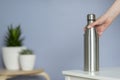 Woman hold steel water bottle on the table at home. Zero waste Royalty Free Stock Photo