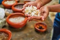 Woman hold washed mined gemstone, on table are many bowl with gemstone