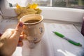 Woman holdig a Cup of autumn tea, coffee, and yellow dry leaves near a window, Royalty Free Stock Photo