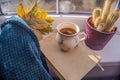 Woman holdig a Cup of autumn tea, coffee, and yellow dry leaves near a window, Royalty Free Stock Photo