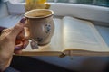 Woman holdig a Cup of autumn tea, coffee, and yellow dry leaves near a window, Royalty Free Stock Photo