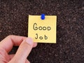 A woman holding an adhesive note with the words good job on it pinned on a cork bulletin board Royalty Free Stock Photo