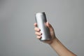 Woman holding aluminum can with beverage on grey background, closeup. Royalty Free Stock Photo