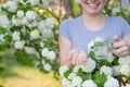 Woman holding an antihistamine tablet and a glass of water while in a blooming garden.