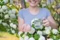 Woman holding an antihistamine tablet and a glass of water while in a blooming garden.