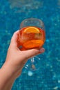 Woman holding aperol spritz cocktail on summer party by the pool. Event celebration concept. Royalty Free Stock Photo
